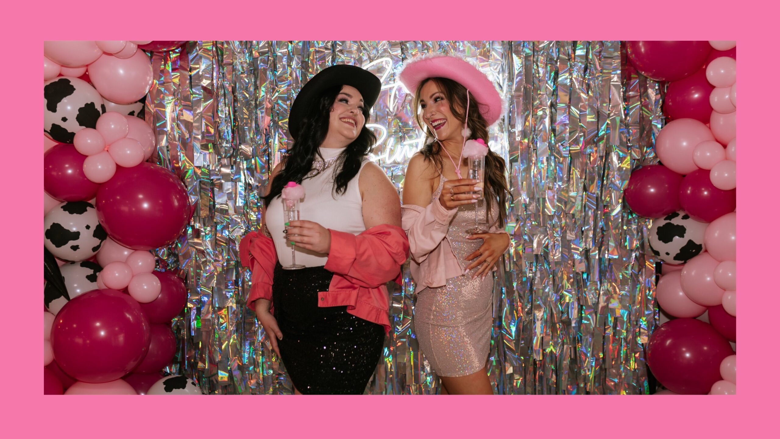 Two girls standing in front of a silver tassel wall.