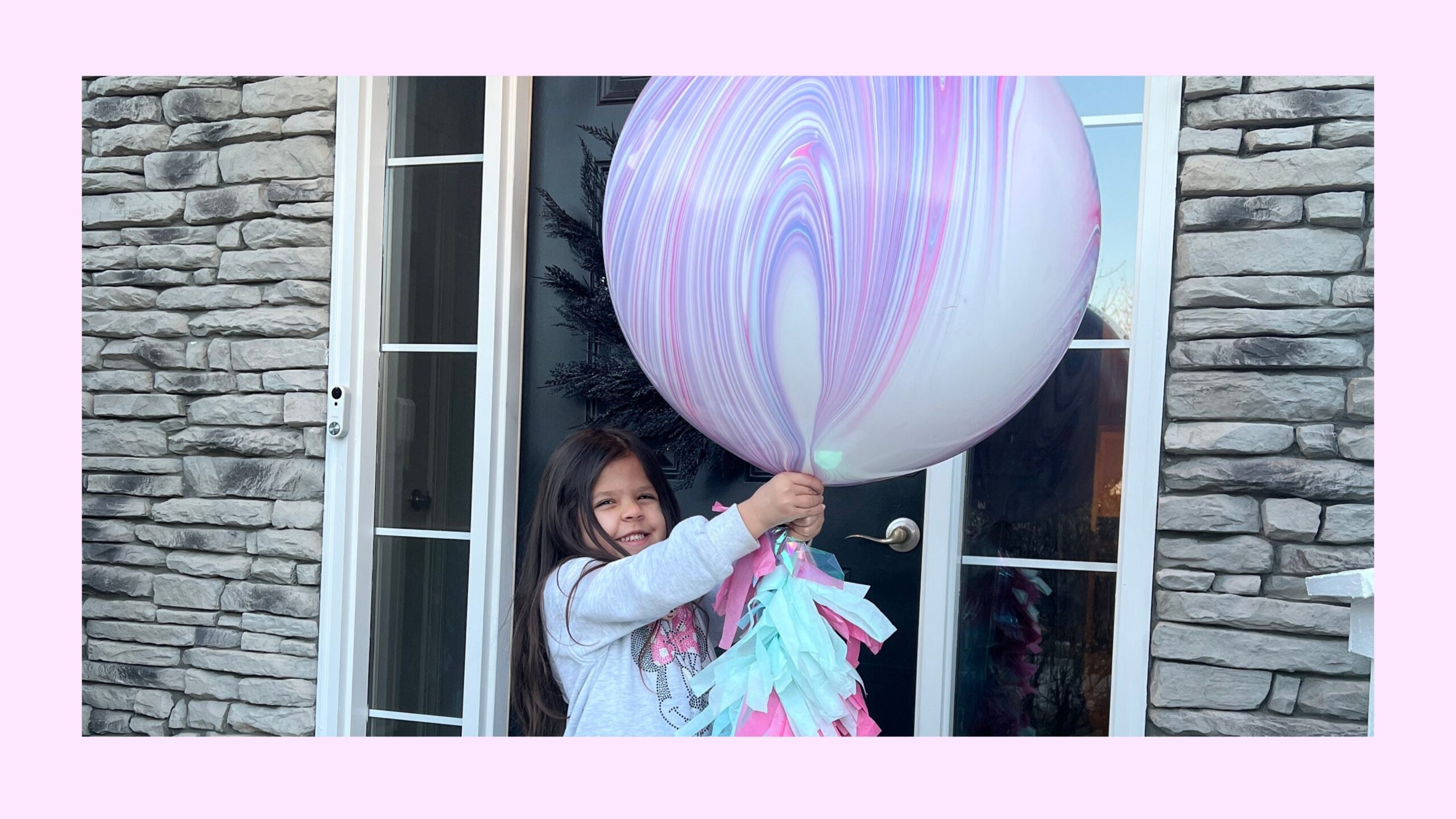 A little girl holding a giant purple helium balloon.