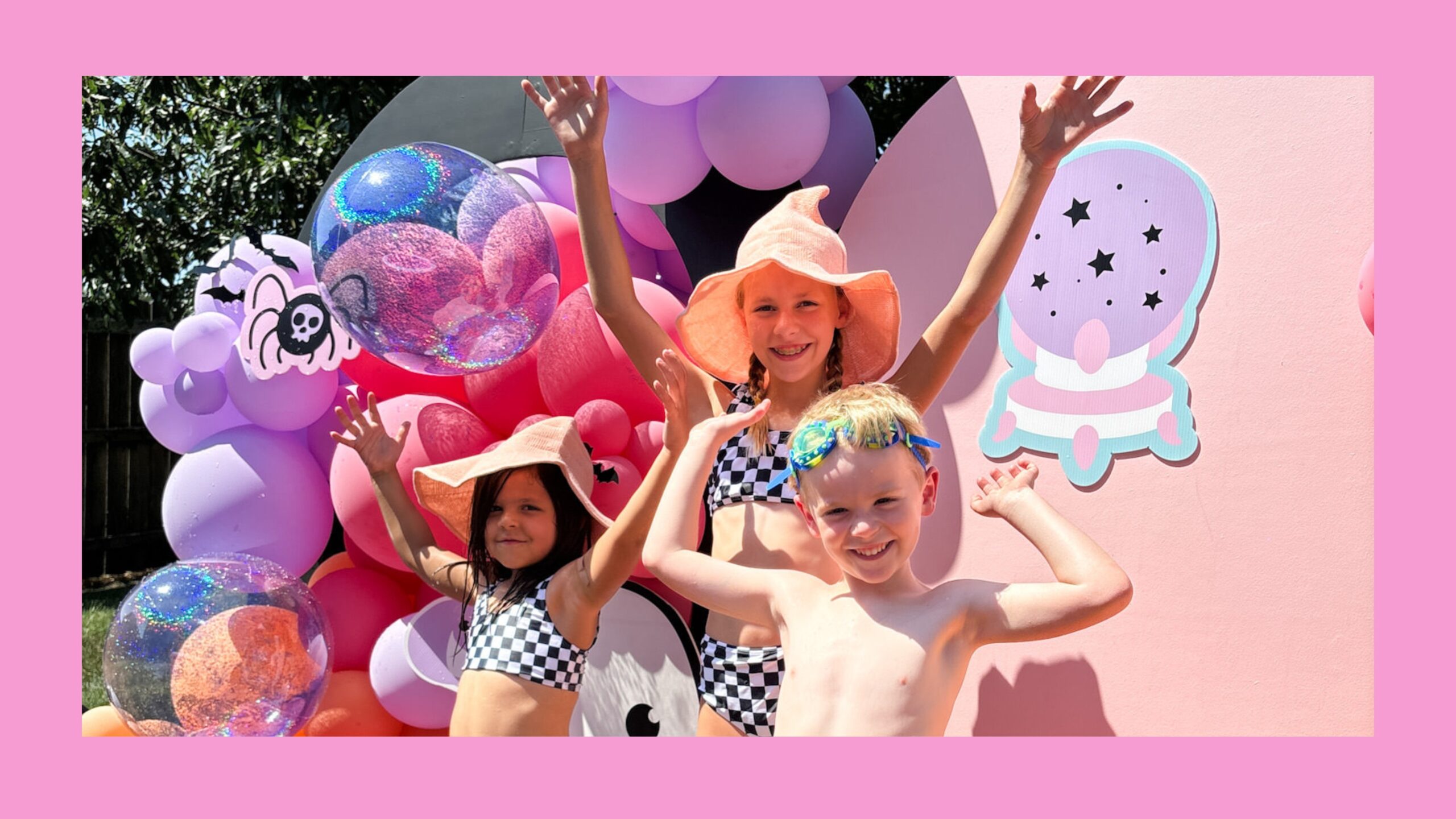 3 children standing in front of colorful Halloween balloons.