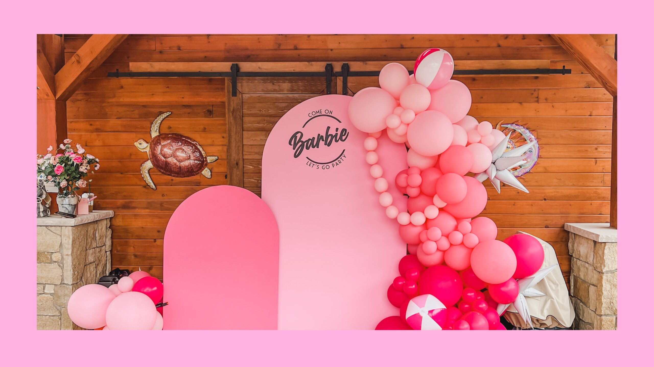Pink balloons surrounding a pink backdrop.