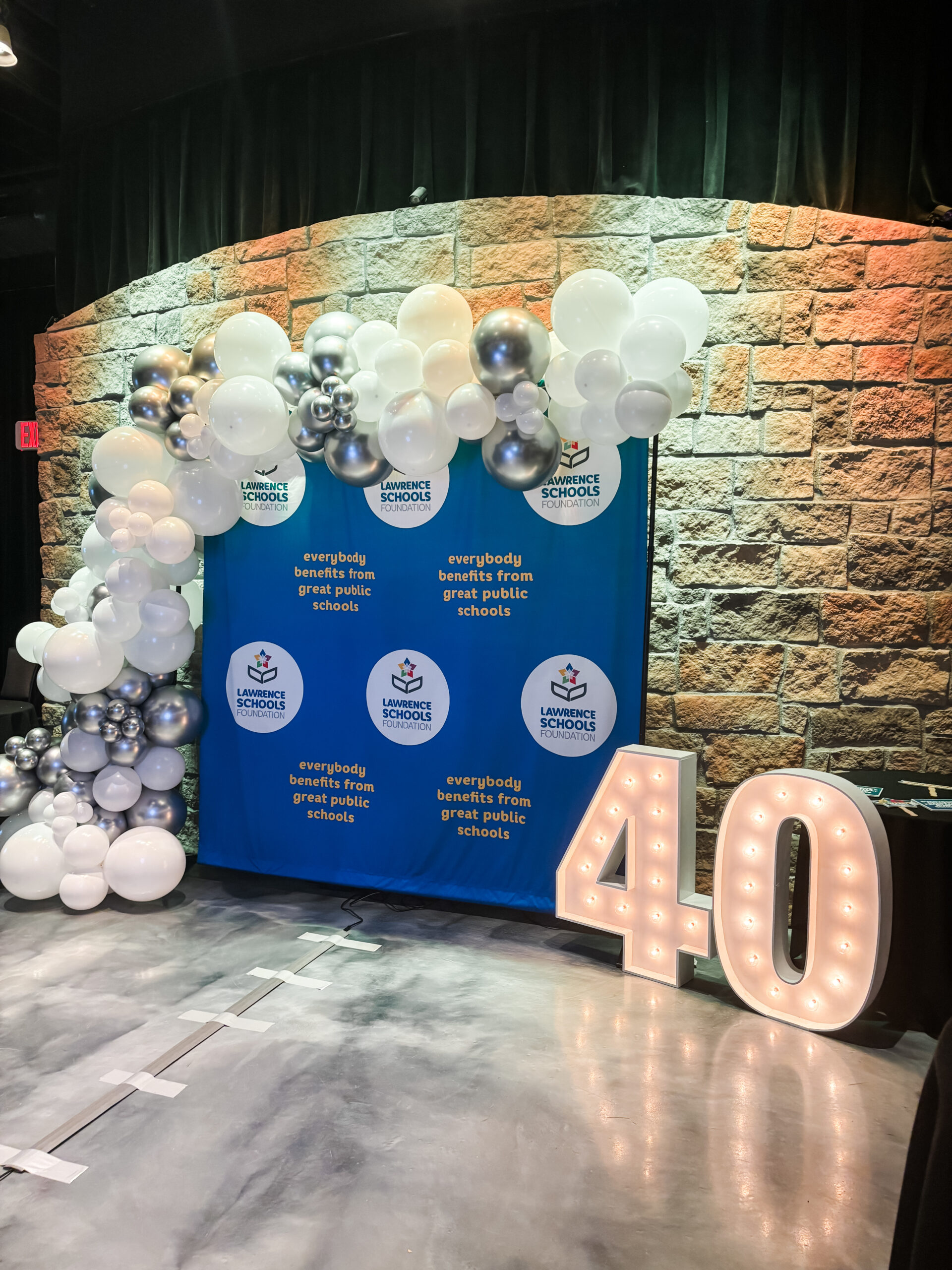 White and silver balloons around blue backdrop with 40 marquee numbers.